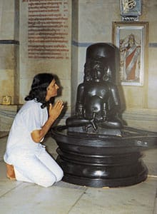 Ypung Amrit Desai kneels at Dadaji statue